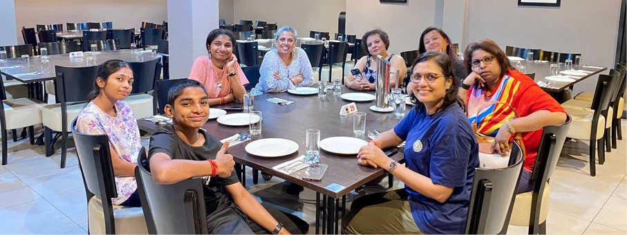 Seven people sitting around a dining table in a well-lit restaurant setting with plates and glasses in front of them.
Description generated by AI
