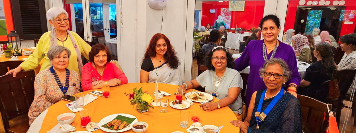A group of women are sitting around a table with food and drinks. They are wearing various outfits and are engaged in conversation. The table is set with plates, cups, and utensils. There are also potted plants and vases on the table, adding to the ambiance. The women are enjoying their time together, creating a warm and friendly atmosphere.

AI generated content