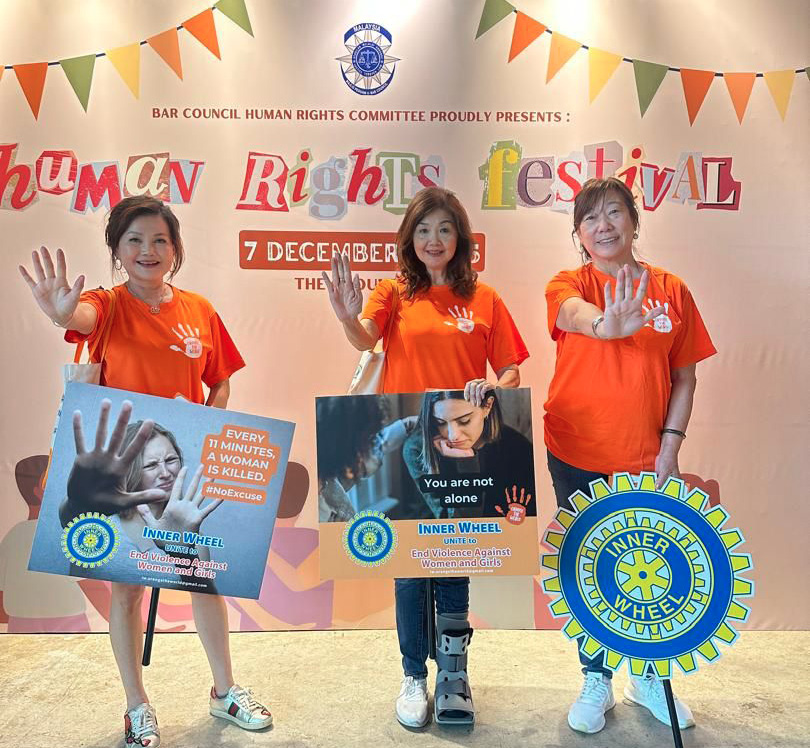 Three women wearing orange shirts stand in front of a sign for the Human Rights Festival.

AI generated content