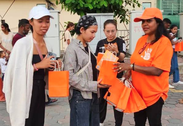 A group of people are standing on a sidewalk, engaged in conversation. One woman is wearing an orange shirt, and another is holding a baby. There are also a few handbags visible in the scene.
AI generated content