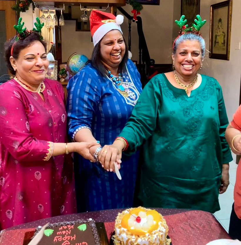 Three women are smiling and holding hands, posing for a picture. They are wearing festive hats and one of them is wearing a Santa hat. The women are standing in front of a cake.

AI generated content