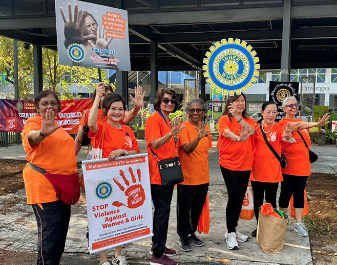 A group of women wearing orange shirts are standing on a sidewalk. They are holding signs and waving at the camera.

AI generated content