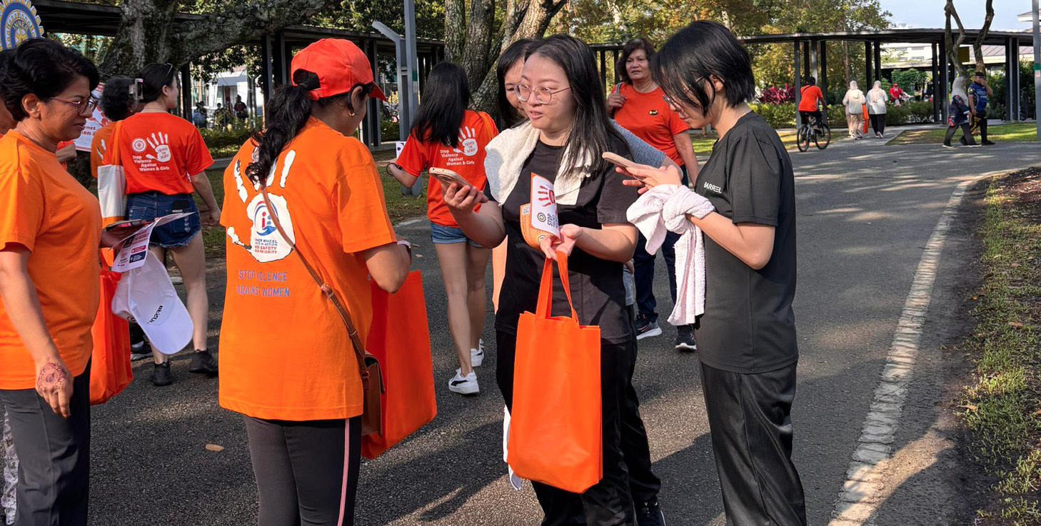 A group of people are standing on a sidewalk, some of them wearing orange shirts. They are engaged in conversation and holding bags.

AI generated content