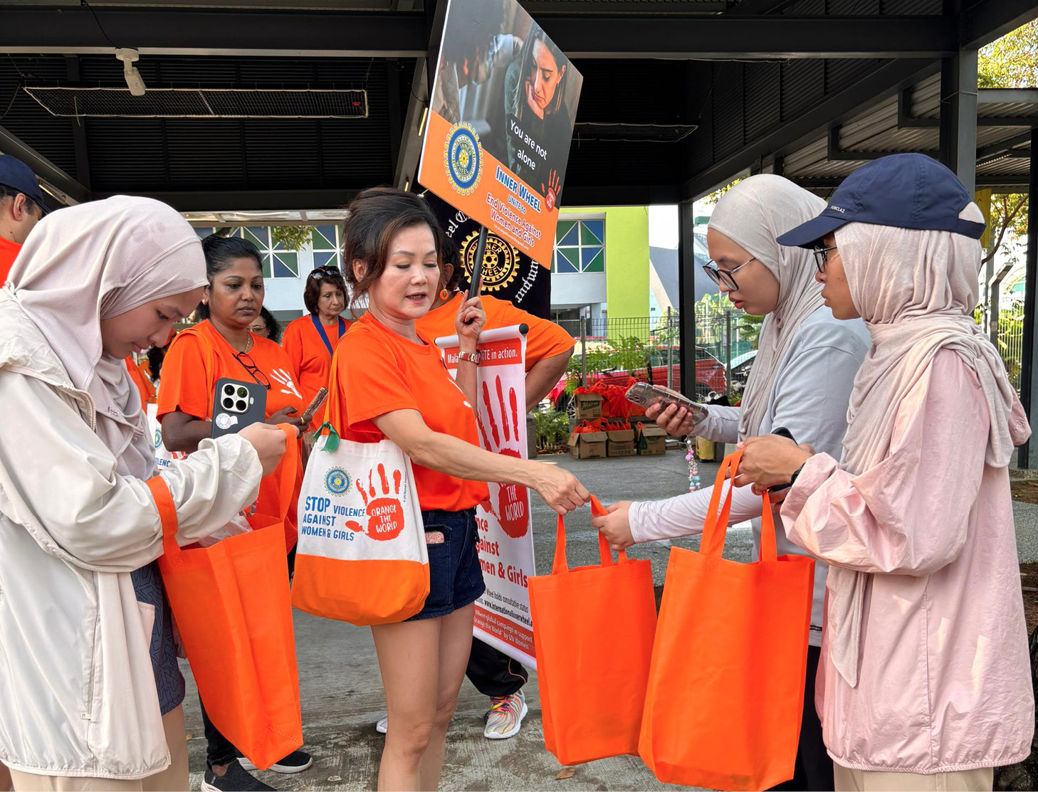 A group of people are holding orange bags, with one woman in an orange shirt handing out the bags to others.

AI generated content