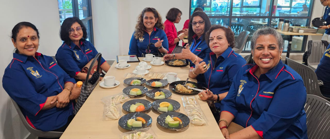 A group of women are sitting around a table with plates of food. They are wearing blue shirts and are enjoying their meal together.
AI generated content