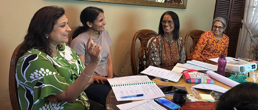 A group of women are sitting around a table, smiling and laughing. They are surrounded by papers, a cell phone, and a laptop. A mirror is also present in the room.

AI generated content
