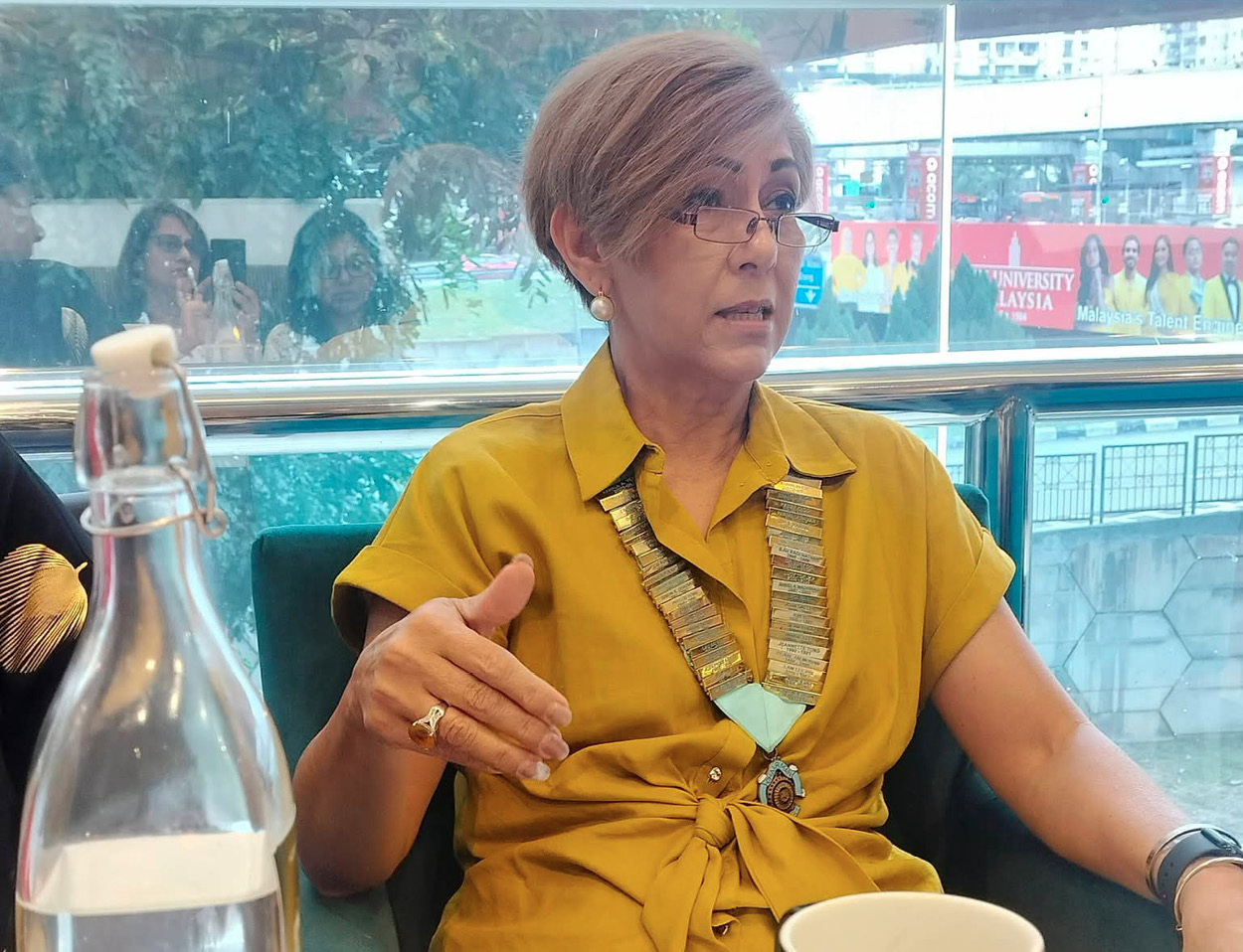 A woman in a yellow shirt is sitting at a table with a cup of coffee in front of her.
AI generated content