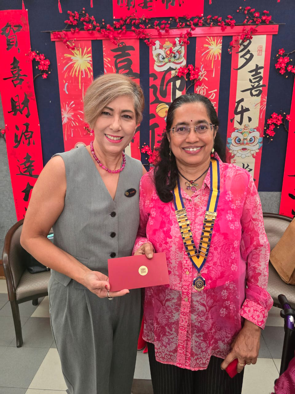 Two women are standing next to each other, one holding a red card. They are both wearing pearl necklaces.
AI generated content