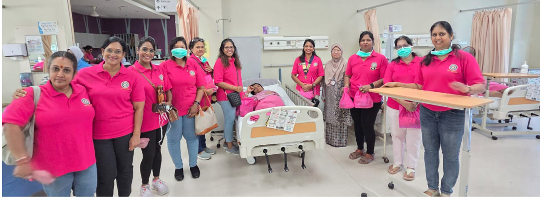A group of people wearing matching pink shirts stand around a hospital bed with a person lying in it, inside a medical facility.

Description generated by AI