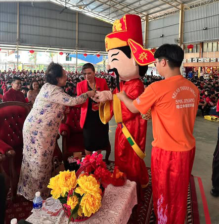 A woman is shaking hands with a man dressed in a red and yellow costume. The man is holding a stuffed animal, possibly a dragon. The woman is wearing a red jacket.

AI generated content