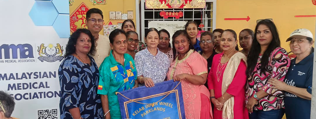 A group of people standing closely together indoors, some holding a blue banner with text, next to a sign that reads Malaysian Medical Association.
Description generated by AI