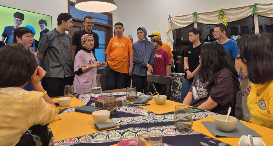 A group of people are gathered around a table with bowls and glasses in a warmly lit room decorated with hanging stars and crescent moons.
Description generated by AI