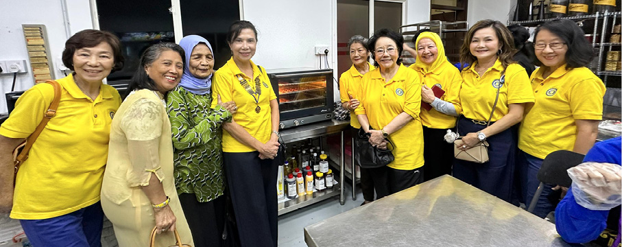 A group of adults wearing yellow shirts stand together smiling in a room with shelves, bottles, and a metal table.
Description generated by AI