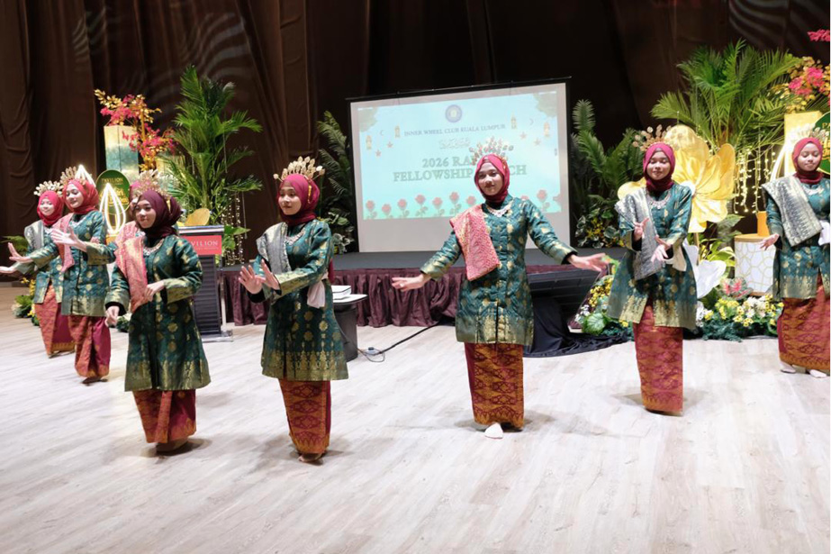 A group of people dressed in traditional attire with patterned skirts and headscarves are performing a coordinated dance on a stage decorated with plants and flowers.
Description generated by AI