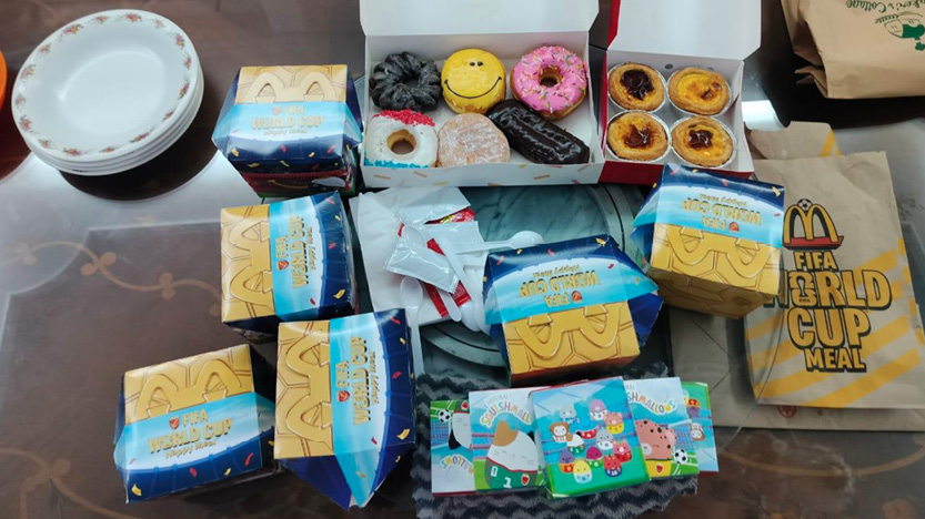 A table displays several McDonald's World Cup Meal boxes, a few open boxes with assorted donuts and pastries, some plates, and colorful collectible cards.
Description generated by AI