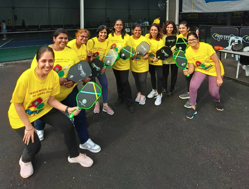 A group of people wearing matching yellow shirts are standing together outdoors holding pickleball paddles and smiling.
Description generated by AI